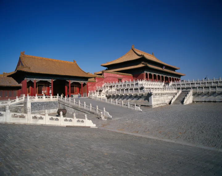 蓝天下的古代宫殿建筑坐落在宽阔的石铺庭院中。