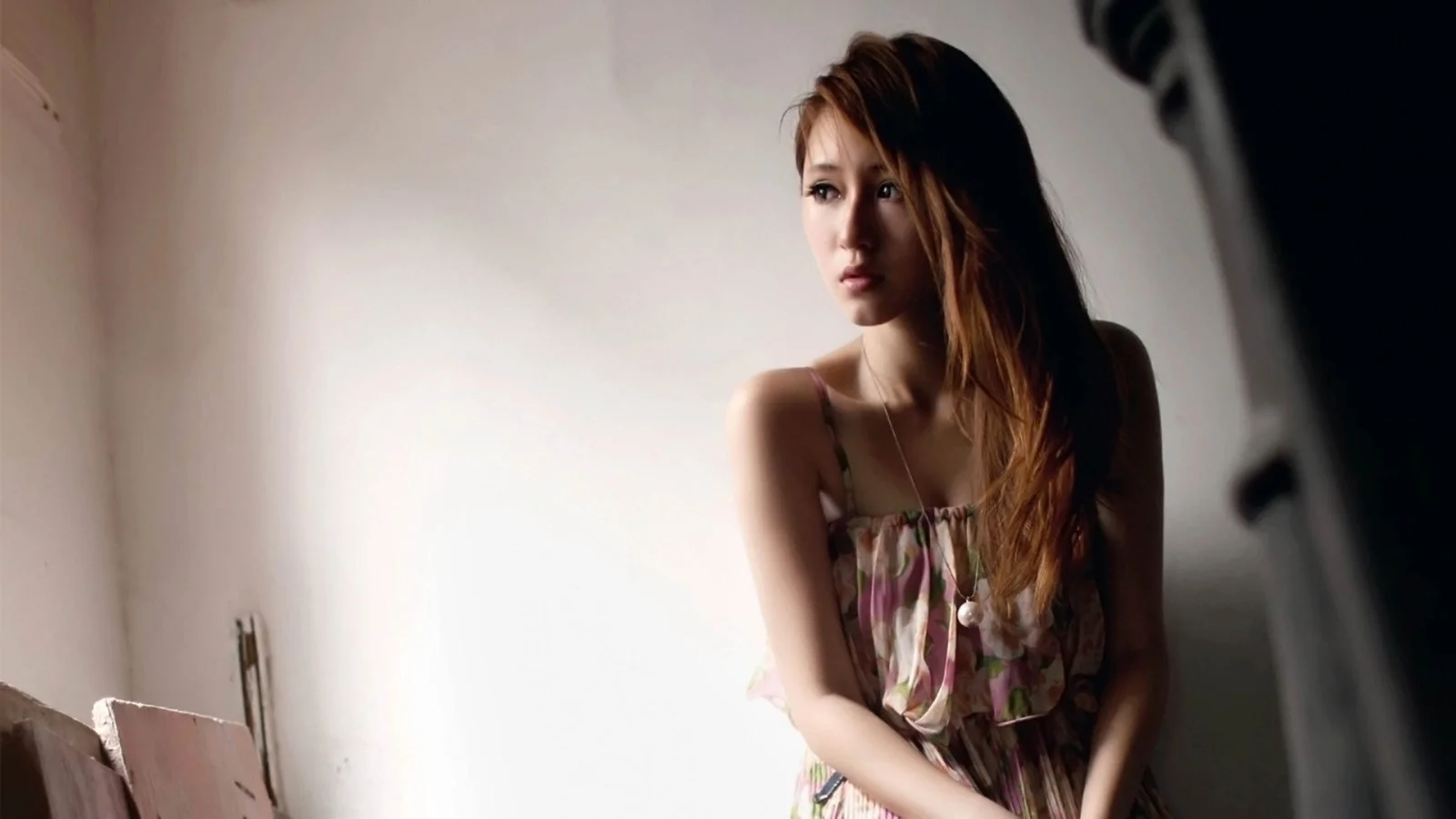 一名身穿无袖连衣裙的成年女性在柔和光线下望向一侧。