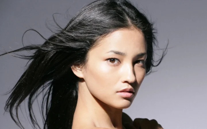 一名黑发成年女性在灰色背景前进行近距离肖像拍摄。