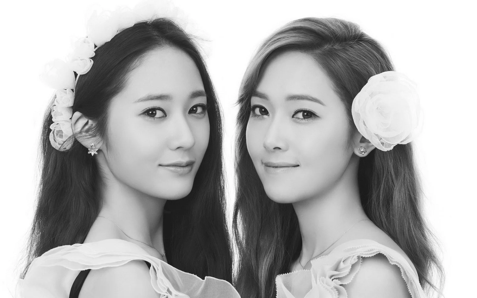 흰색 꽃 장식을 착용한 두 성인 여성이 흰 배경 앞에서 흑백 스튜디오 인물 사진을 촬영하고 있다.