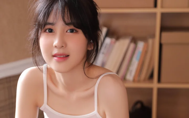 一位成年女性在室内书架前面向镜头微笑。