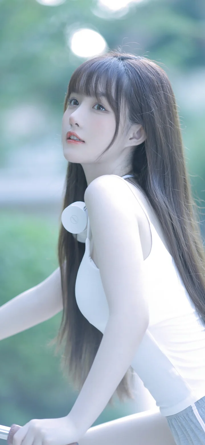 一名长发女子在柔和的户外背景前回头看向镜头，胸前佩戴白色耳机。