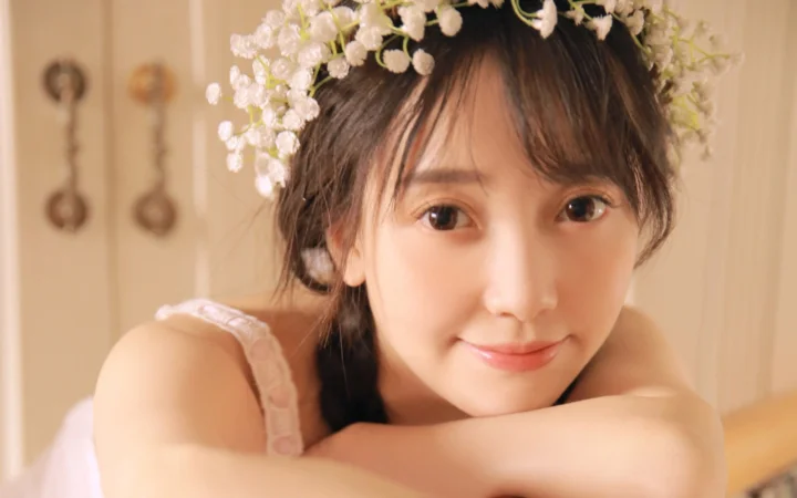 白い花冠を身につけた女性が、室内の柔らかな光の中で微笑んでいる。