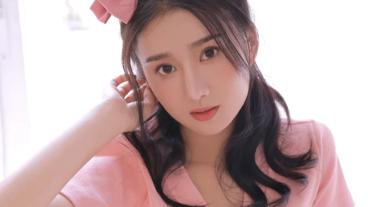 一名成年女性身穿粉色上衣，近距离面对镜头。