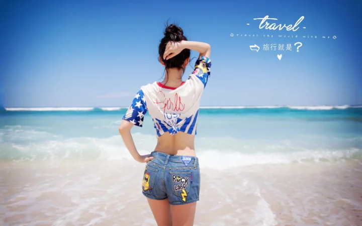 一名女子背对镜头站在浅海水中，面向蓝色海洋。