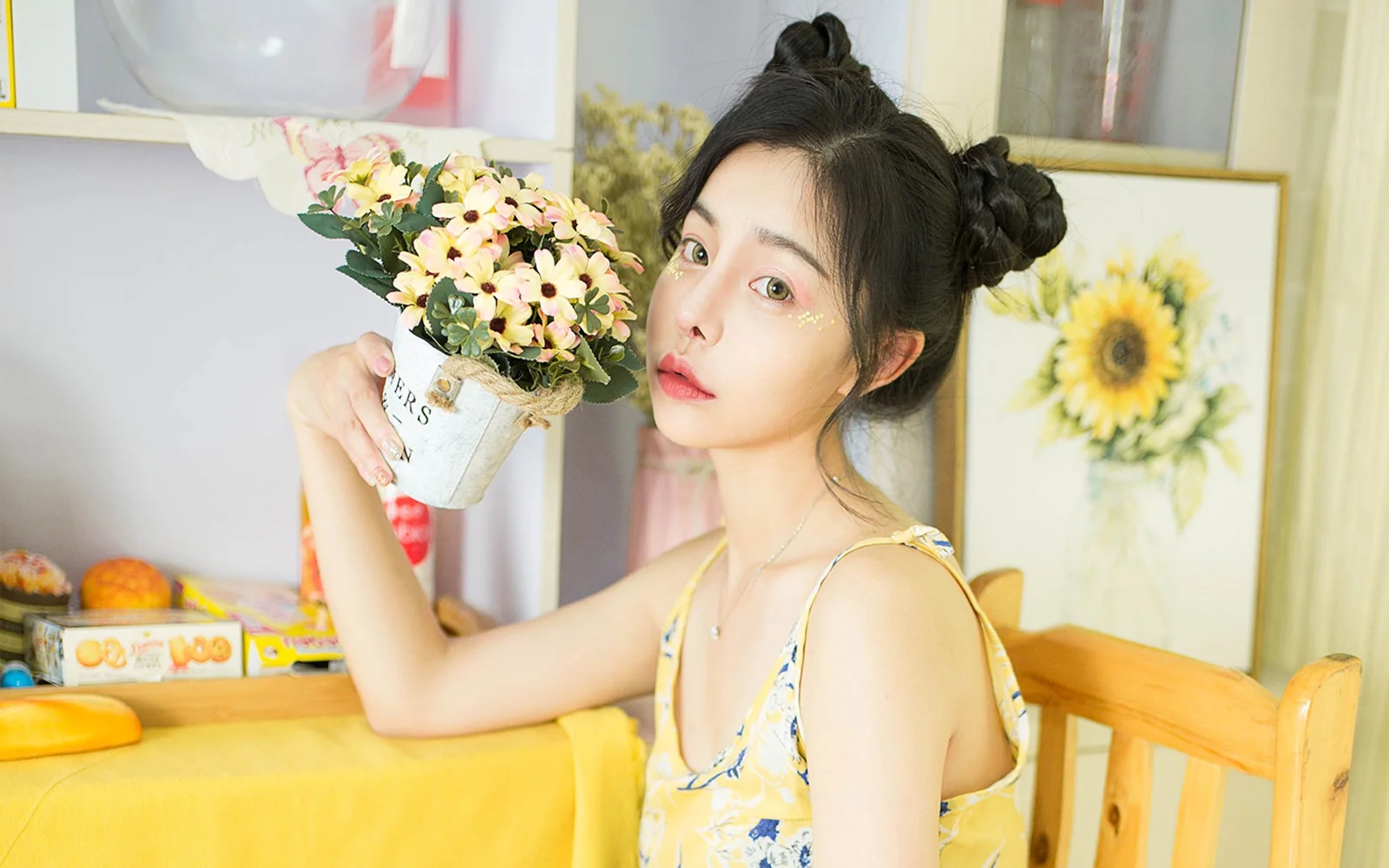 一位成年女性在室内手捧花束坐在桌旁。