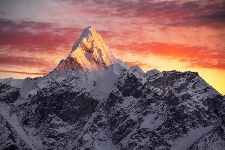 夕阳映照下的雪山在绚丽晚霞中巍峨耸立。