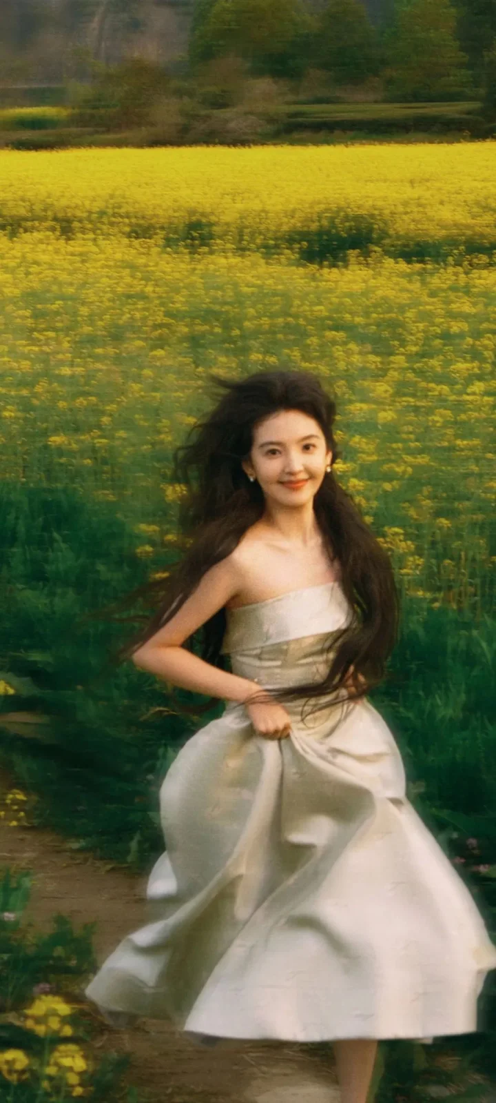 一名身穿白色长裙的女子站在黄色花田中。