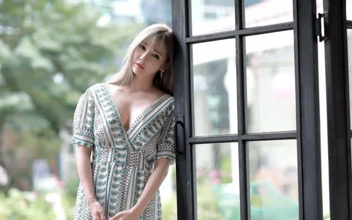 一名女子穿着图案连衣裙站在窗边。