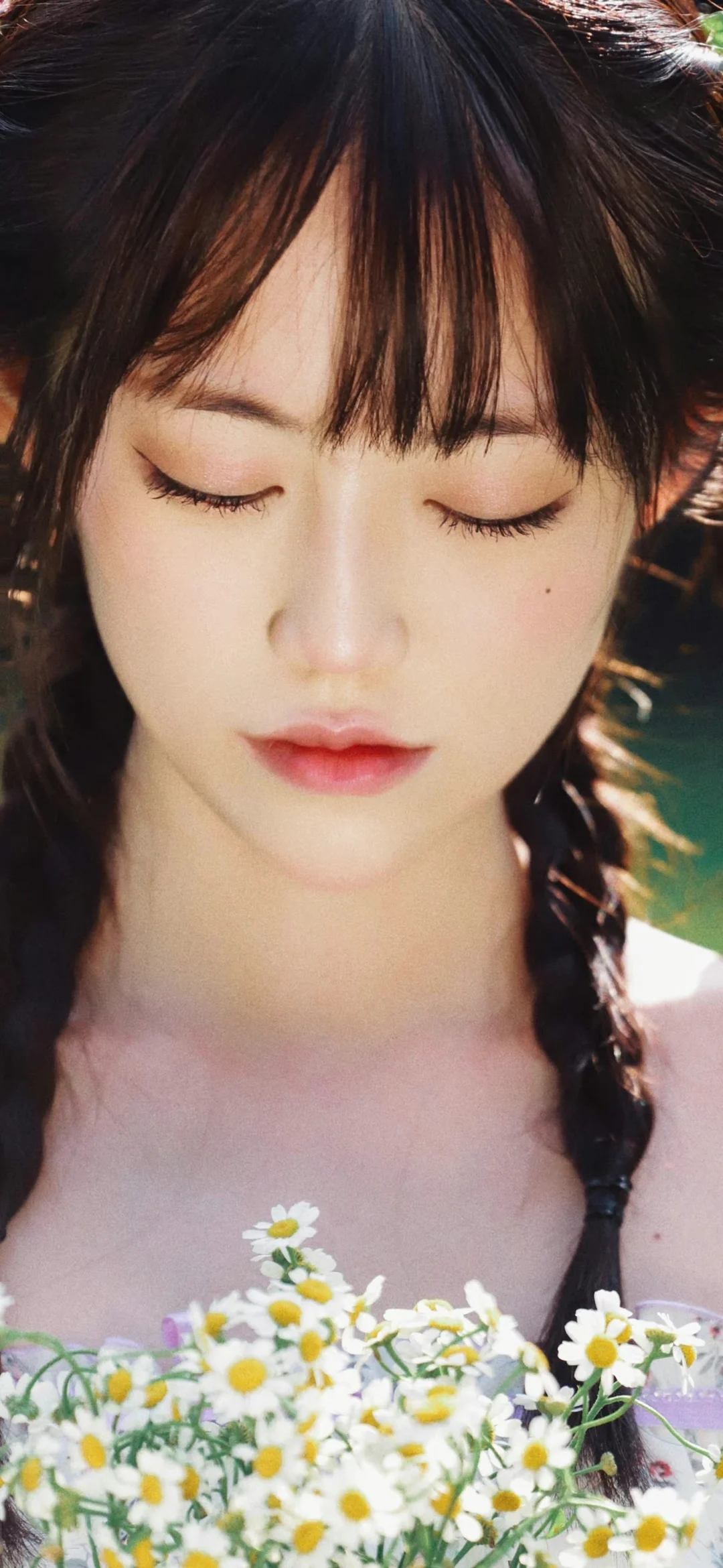 一位闭着眼睛、留着编发的女性怀抱一束白色雏菊。