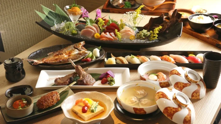 桌面上摆放着寿司、烤鱼、汤品、茶具和多道日式料理。