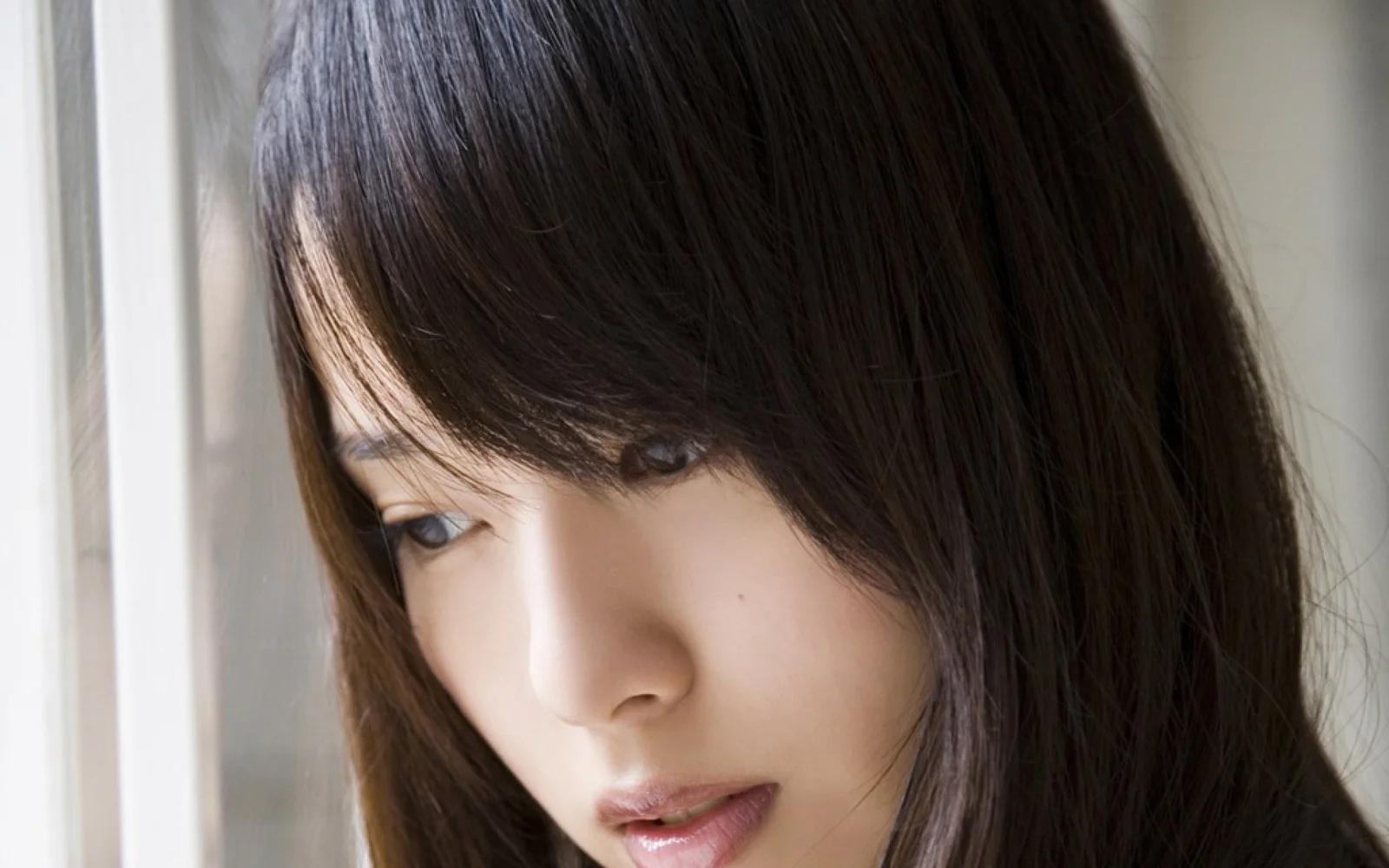 一位棕色長髮女性靠近窗邊，側臉在柔和光線下清晰可見。