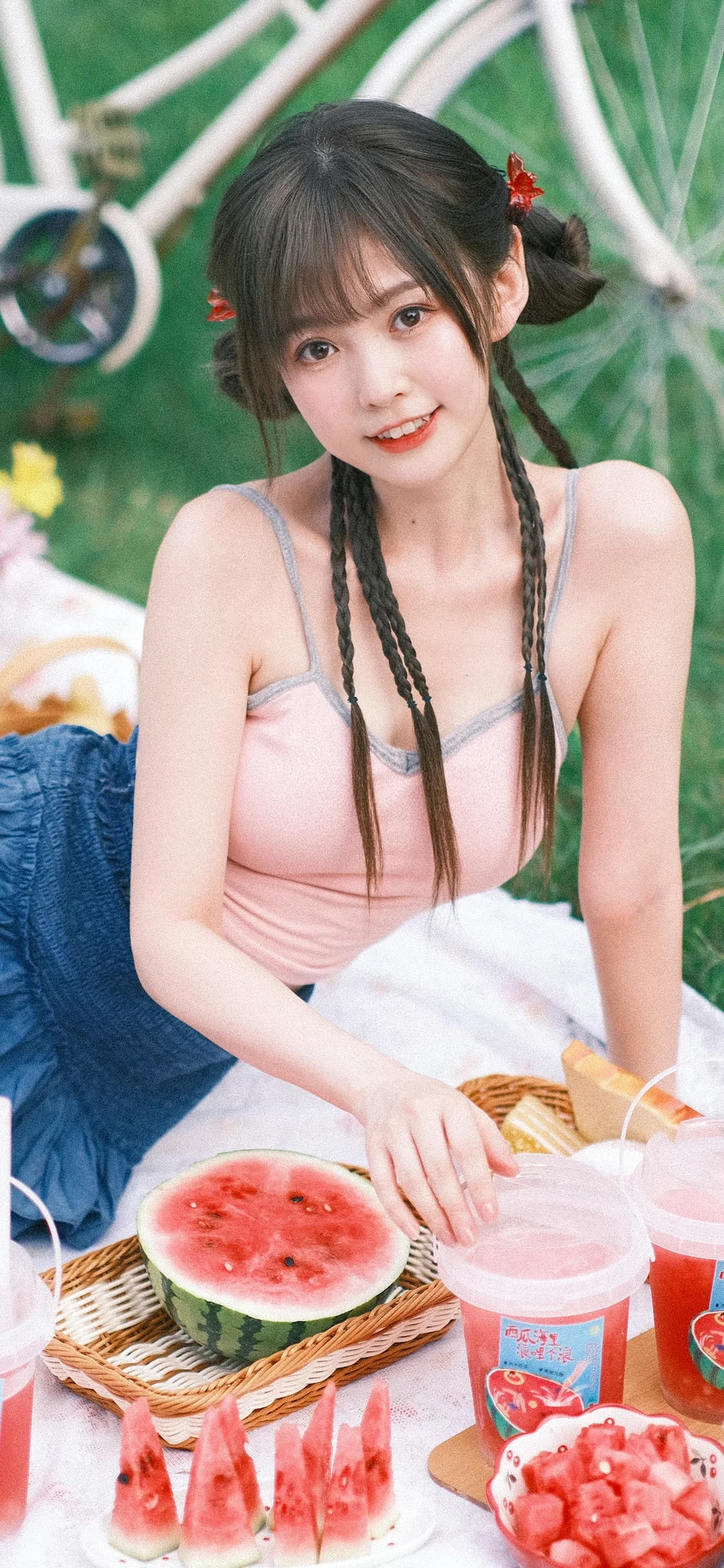 一名扎着双辫的女性坐在户外野餐场景中，面前摆着切开的西瓜。