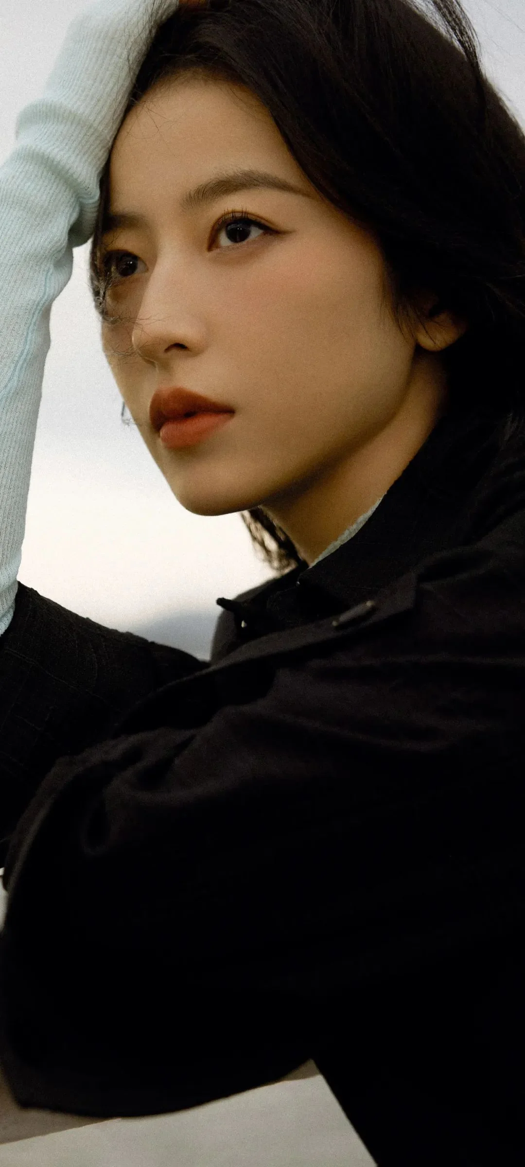 검은색 코트를 입은 성인 여성을 가까이서 담은 측면 초상 사진이다.