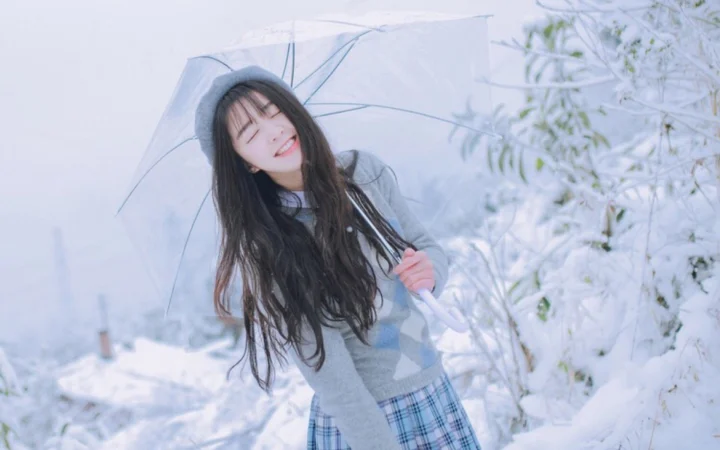 一名女子在白雪覆盖的户外撑着透明雨伞微笑。