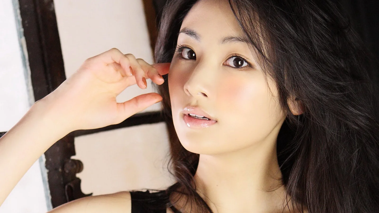 一名长发女性面对镜头的近距离肖像，背景简洁明亮。
