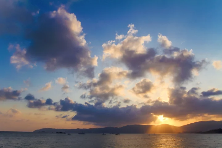 夕阳照耀着海湾、远山与层叠云彩，海面映出金色光芒。