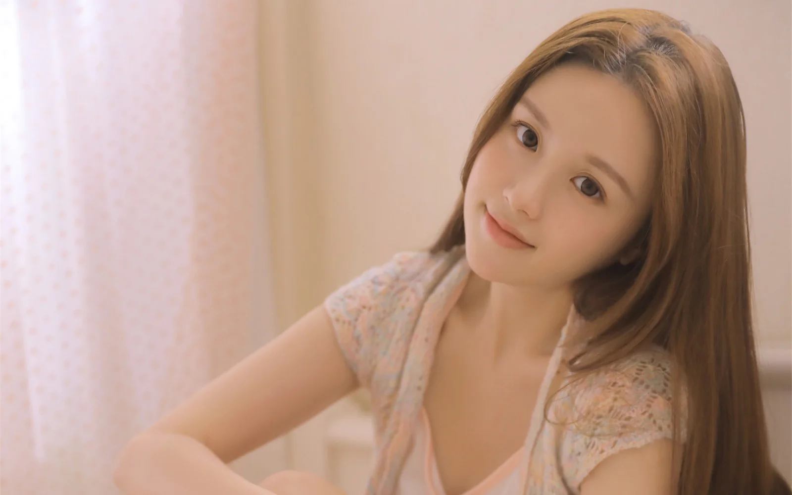 一名棕色长发女性在柔和暖光中面对镜头微笑。