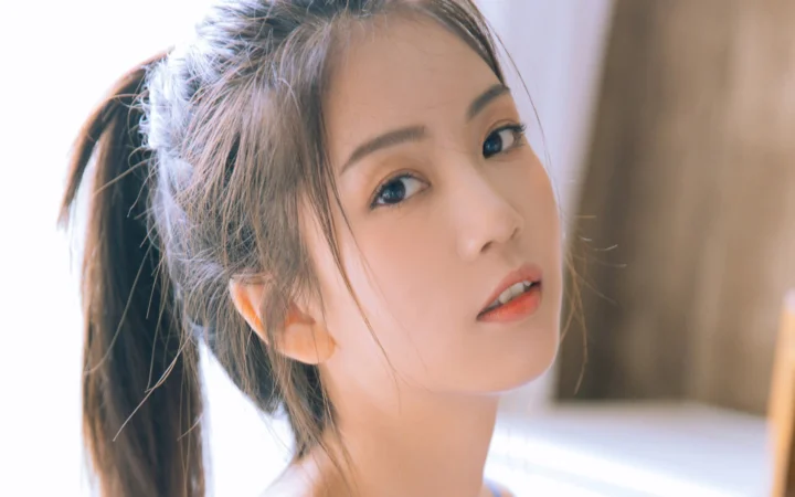 一名綁著馬尾的成年女性在柔和光線下近距離望向鏡頭。
