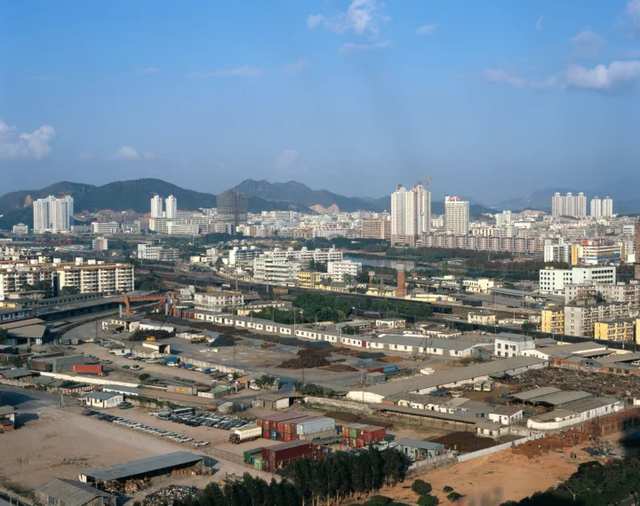 蓝天下的城市建筑、工业区与远山构成开阔的城市全景。