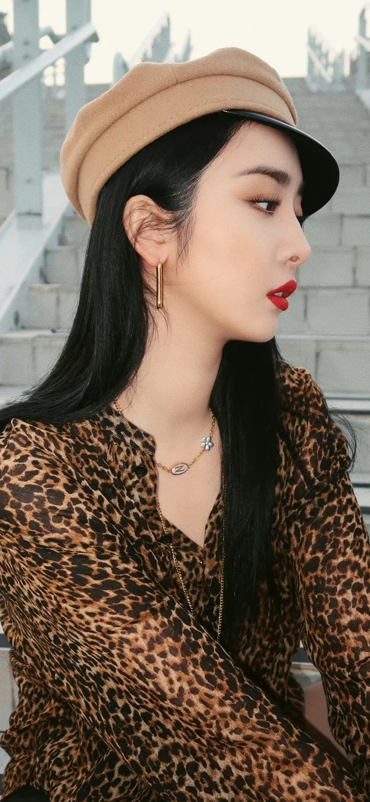 一名戴着贝雷帽、穿豹纹上衣的女性在台阶前侧脸入镜。