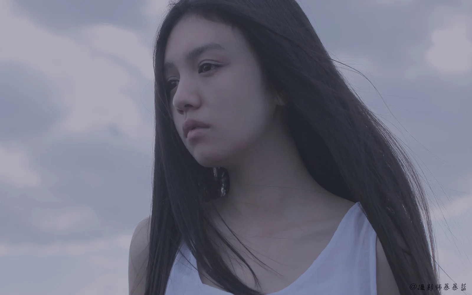 一名長髮女性在雲層天空前的近景肖像。