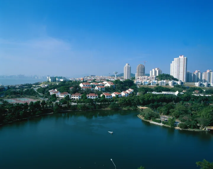湖泊前方是一片由高层建筑和低层住宅组成的城市天际线。