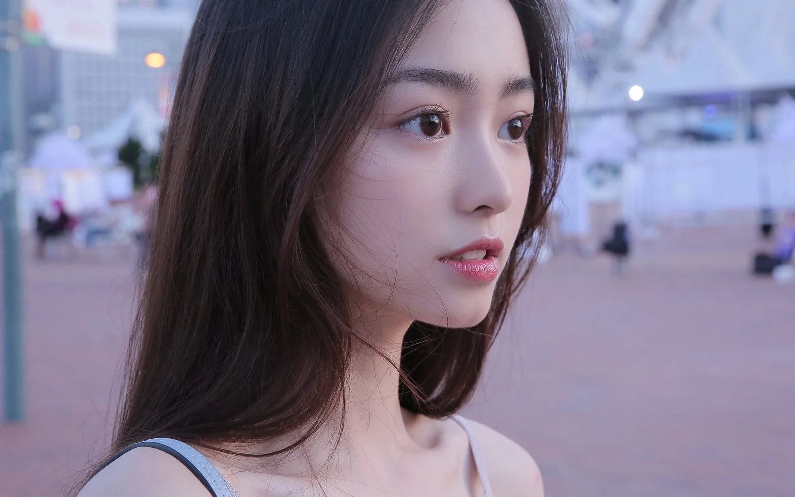 一名成年女性在城市街头的近距离侧脸肖像，背景呈现柔和的虚化光影。