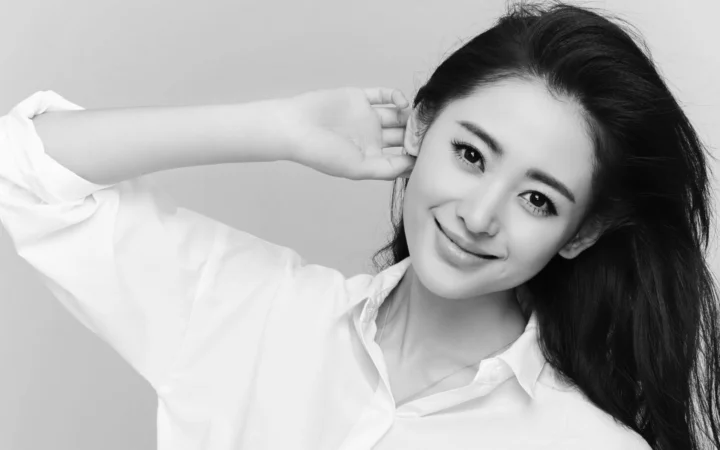一位成年女性身穿白色衬衫，以黑白影像呈现微笑侧头的人像特写。