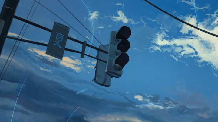 アニメ風の信号機が青空と雲を背景に吊り下がっている。