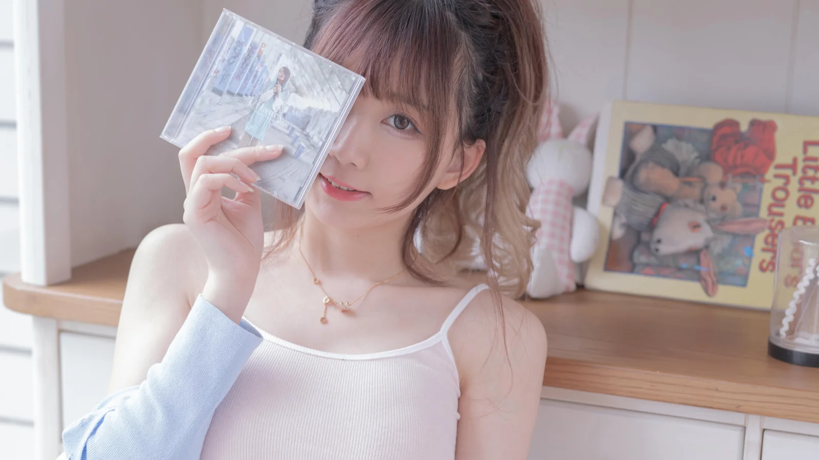 一名女性在室內窗邊手持一本透明封面的畫冊面向鏡頭。