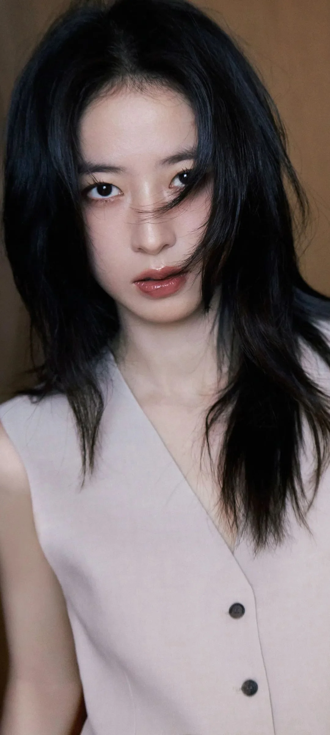 長い髪の女性が淡い色のノースリーブトップスを着てカメラに向かうポートレート写真です。