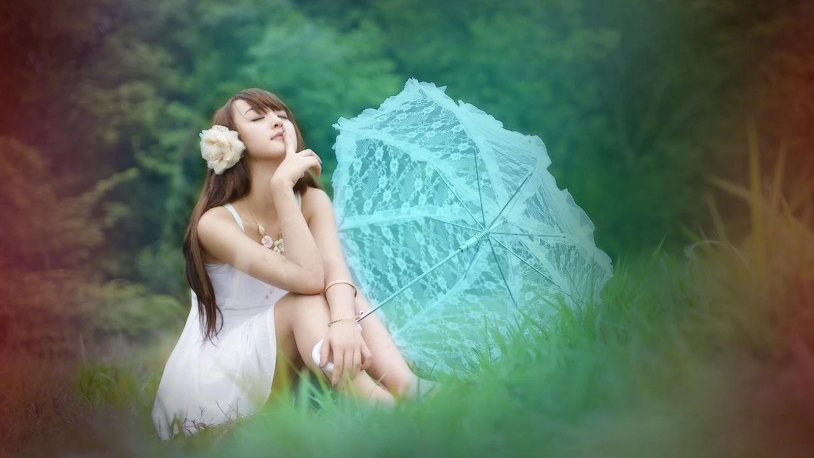 一名身穿白色连衣裙的女子坐在森林草地间，身旁撑着一把浅蓝色叶纹伞。