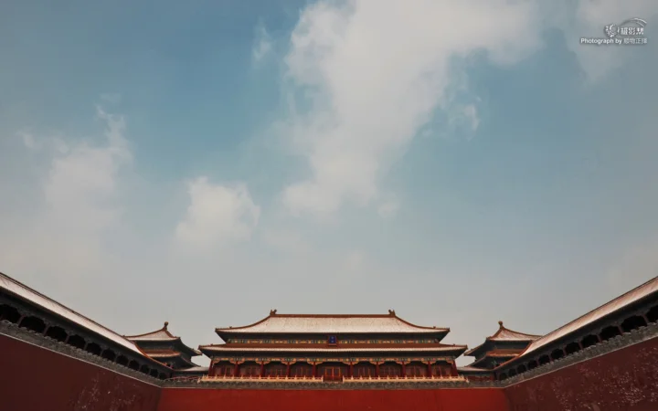 红墙环绕的传统宫殿建筑坐落在蓝天白云下。