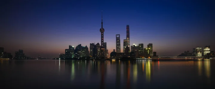 暮色中的城市天际线倒映在平静的水面上，建筑灯光与桥梁灯带清晰可见。