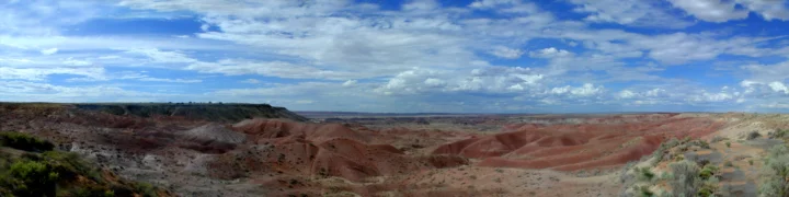 蓝天下延展开来的红色峡谷与荒漠地貌构成壮阔的全景画面。