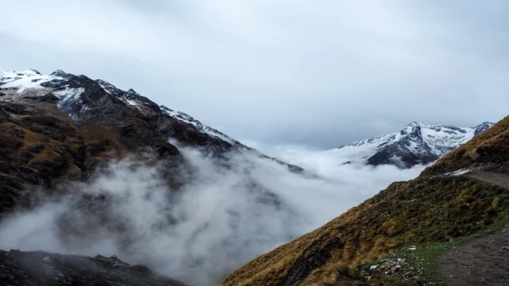 群山之间云雾弥漫，积雪覆盖的山峰在阴天背景下延伸至远方。