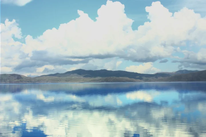 宁静的湖面倒映着远山与高空中蓬松的白云。
