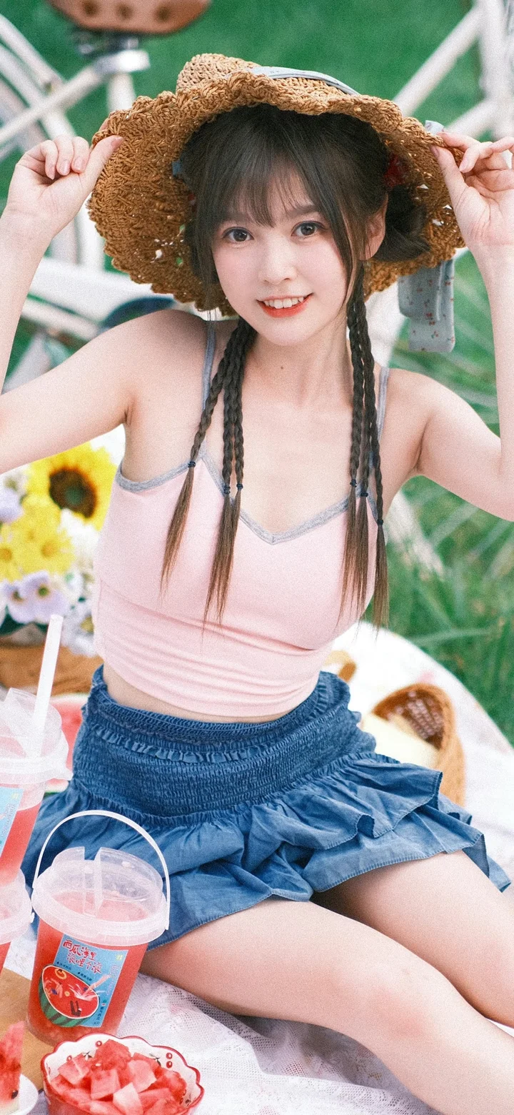 一名戴草帽、扎着长辫子的女性坐在户外野餐场景中。