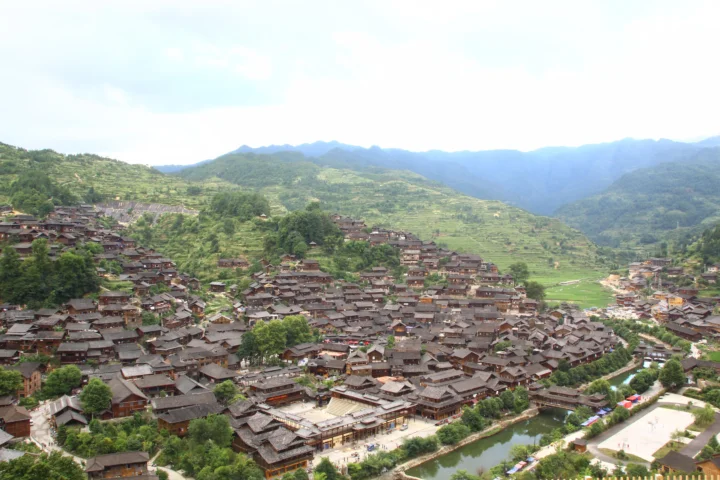 群山环抱的传统村落沿着溪流铺展在绿色山谷中。