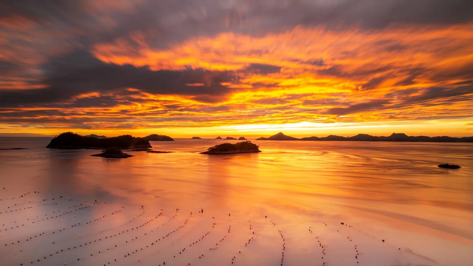 金色の夕焼けが穏やかな海面と遠くの島々を照らしている。