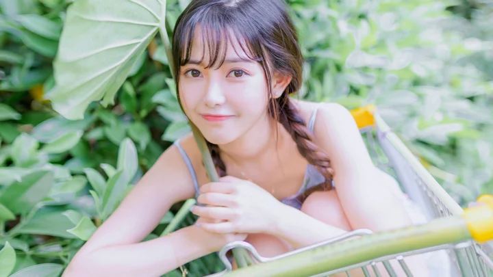 一位女子在茂密绿叶和自行车旁看向镜头。