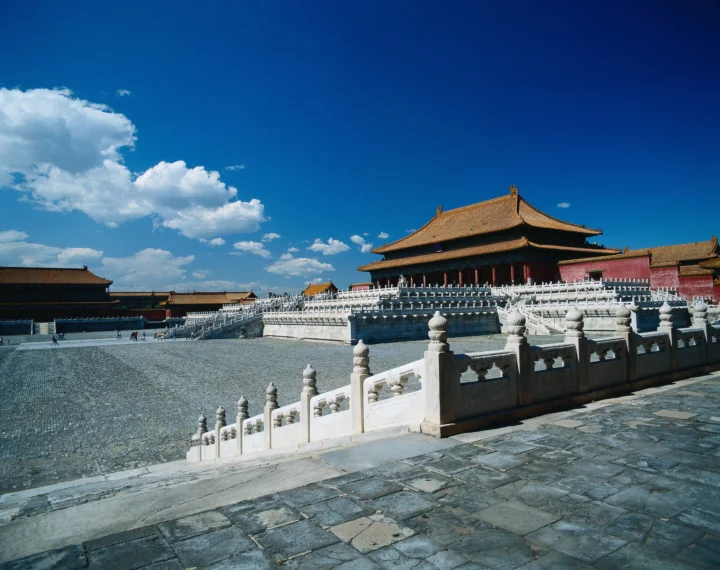 蓝天下的古典宫殿建筑坐落在宽阔的石砌庭院与白色石栏杆之间。