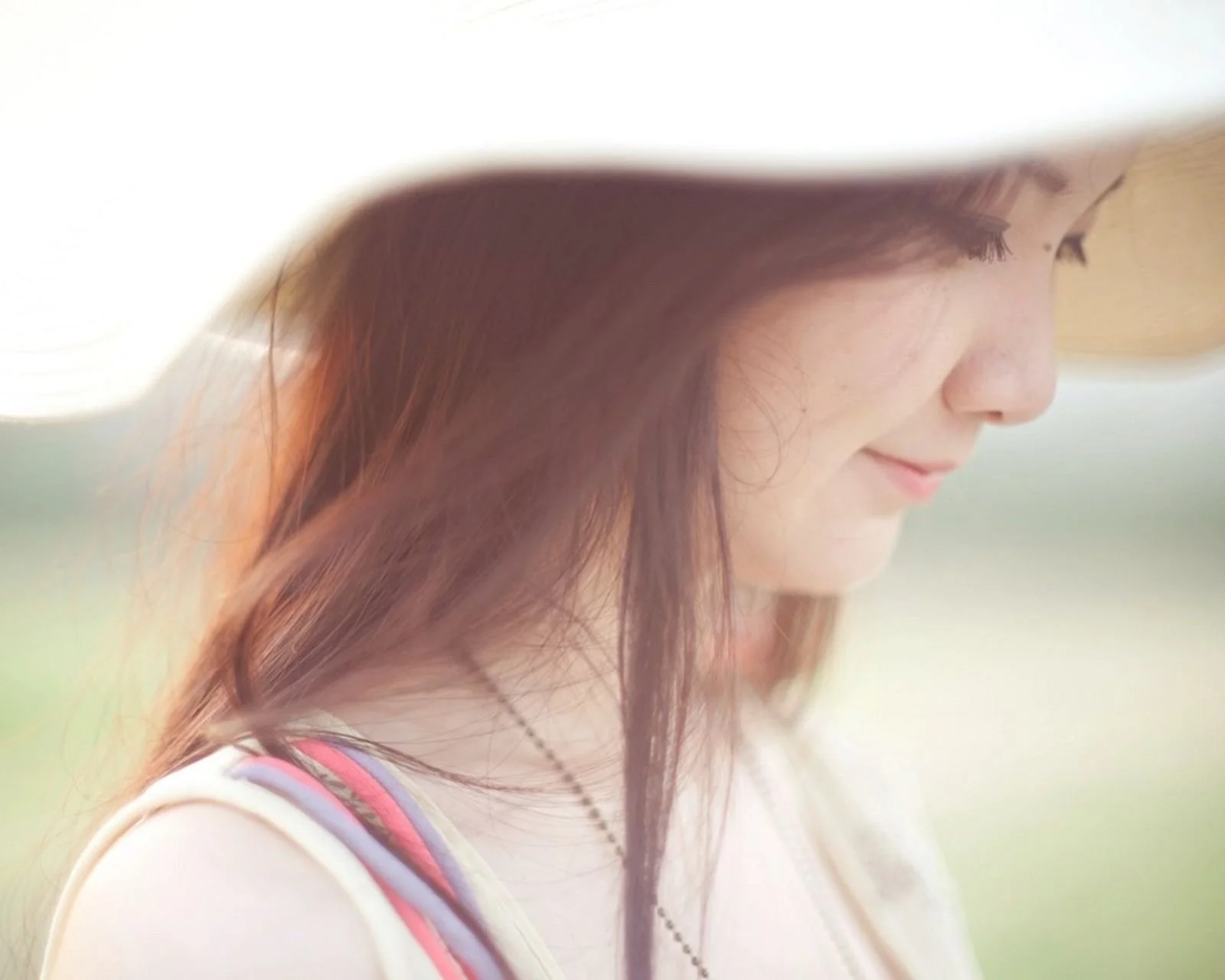 밝고 흐릿한 배경 앞에서 긴 머리의 성인 여성이 부드러운 옆모습을 보여 준다.