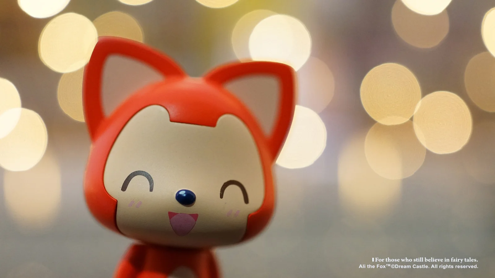 赤いキツネ姿のカートゥーンキャラクターが、暖色のぼけた光を背景に微笑んでいる。