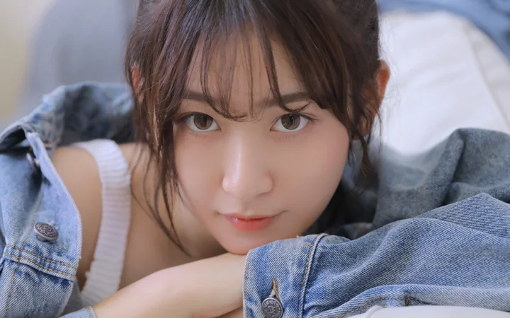 一名成年女性穿着牛仔服饰，近距离望向镜头。