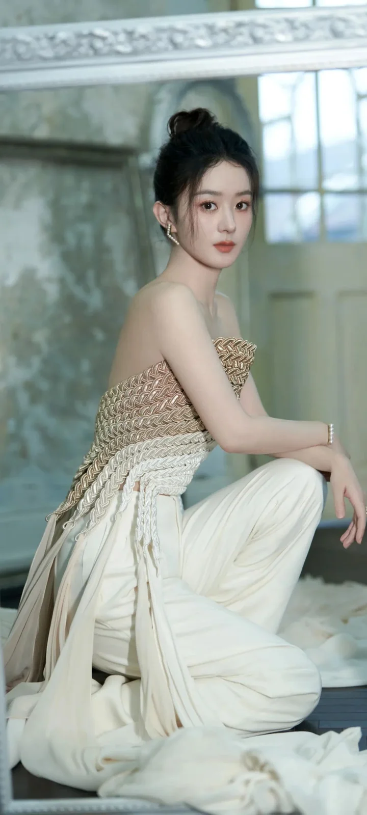 一位成年女性坐在室内，穿着白色服装和纹理上衣。