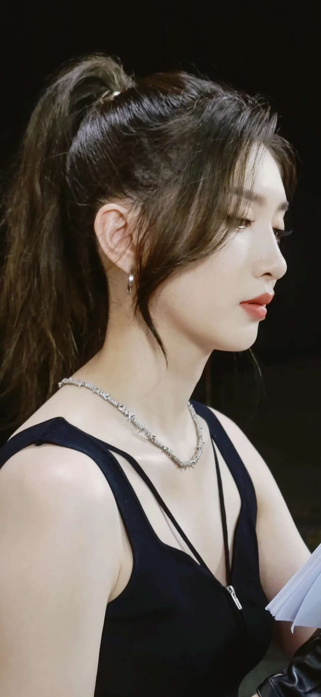 一名成年女性身穿黑色無袖服裝，以側臉姿態面向右側。