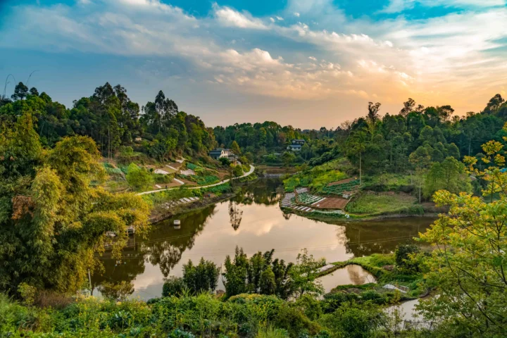 夕阳映照下的林间湖泊、田地与蜿蜒水岸构成宁静的自然景观。