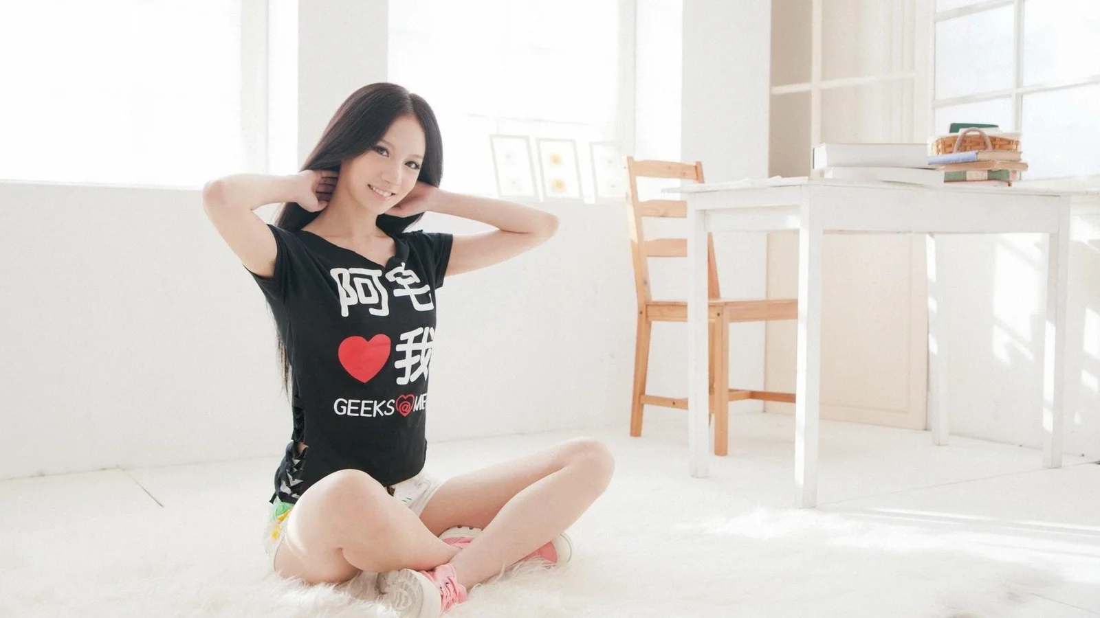 一名成年女性坐在明亮的白色室内地面上。